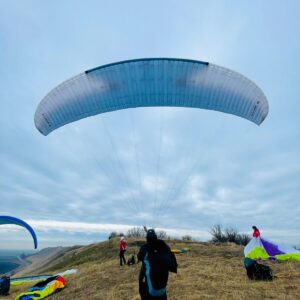 A paraglider pilot soars through the sky with a Niviuk Ikuma 2 paraglider, enjoying breathtaking views and a sense of freedom.