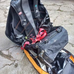 A professional paraglider harness, reversible design, displayed against a scenic backdrop.