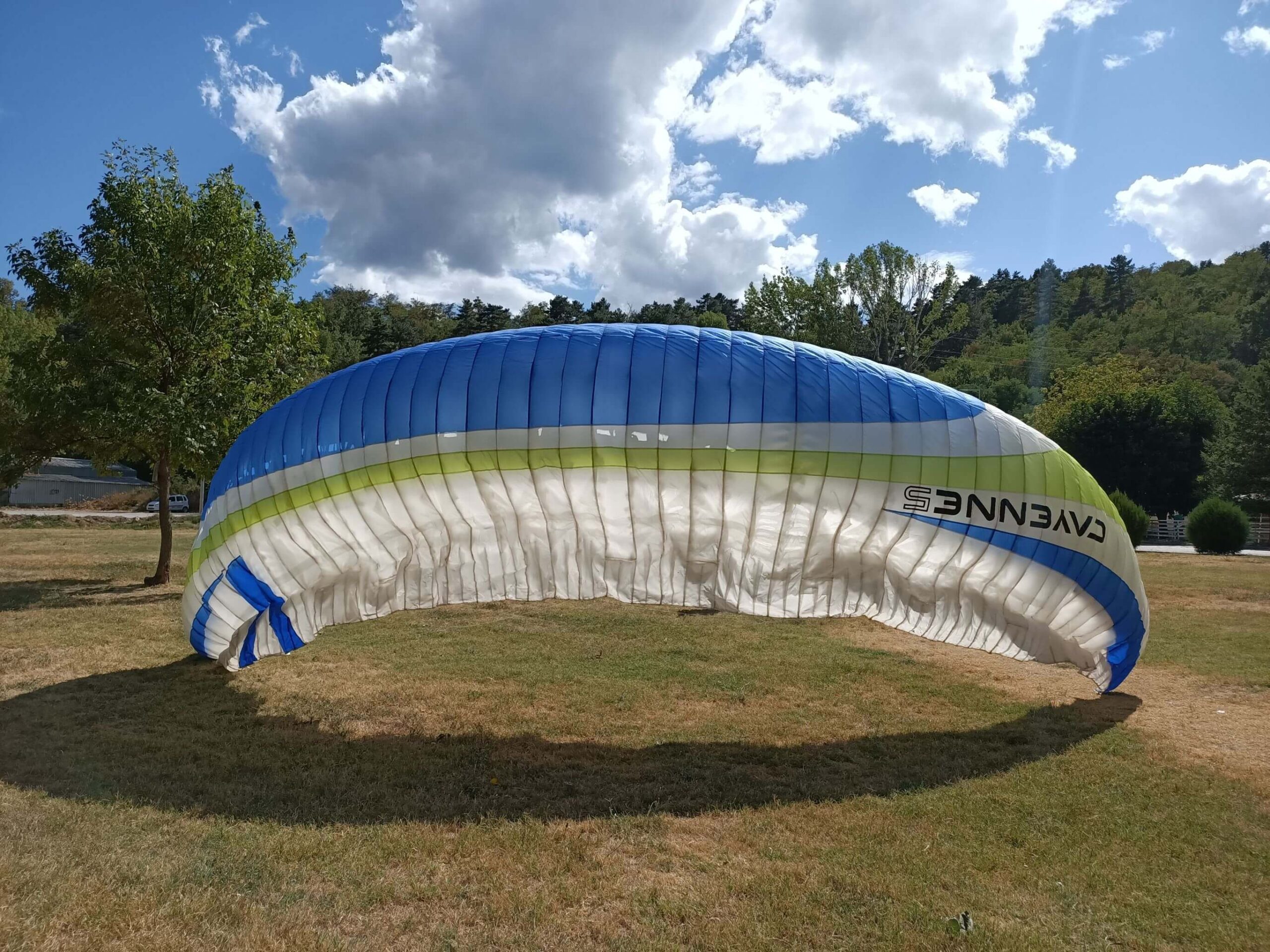 A Skywalk Cayenne 5 paraglider lying neatly in a garden, showcasing its vibrant colors and excellent condition.