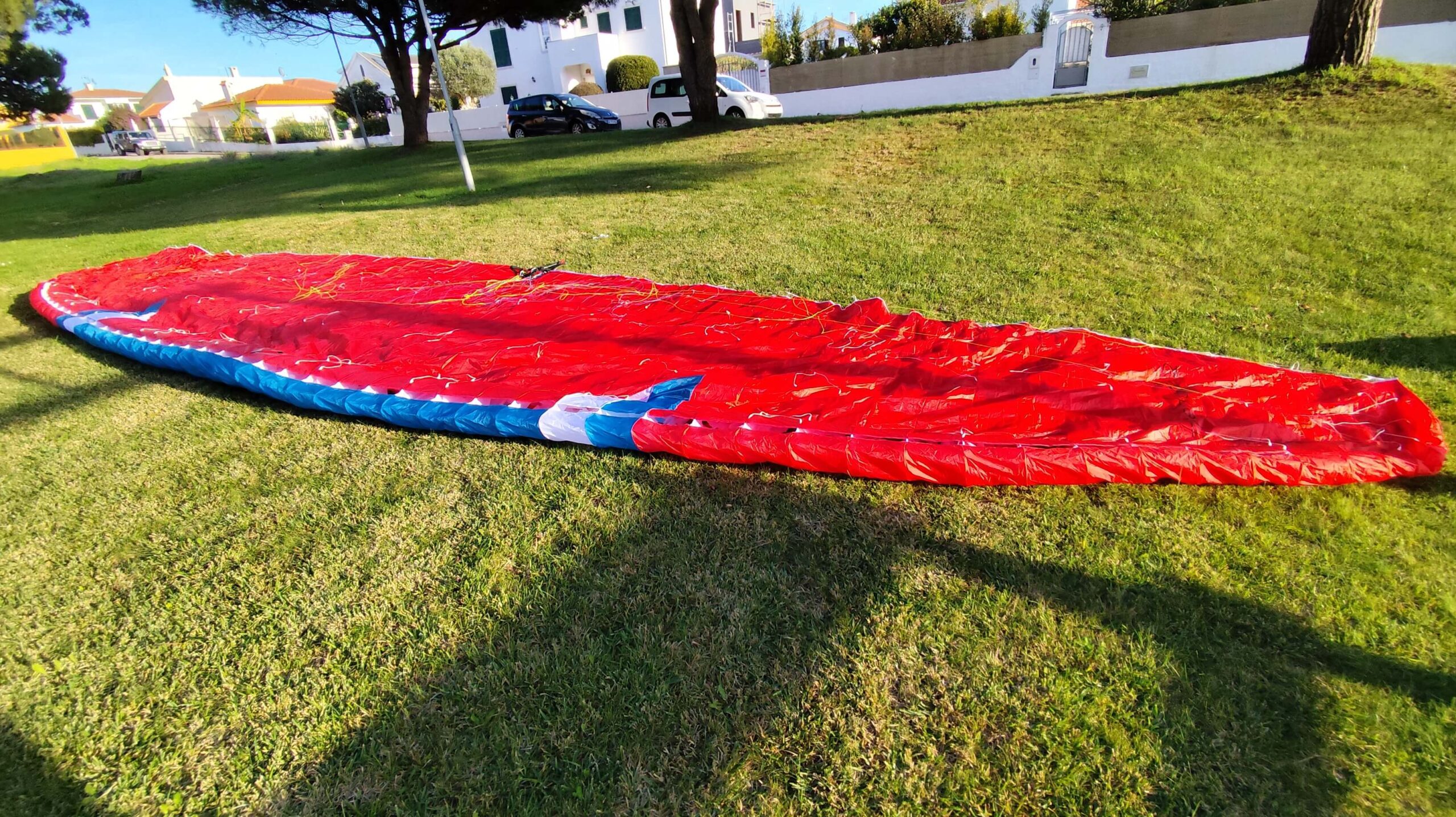 "Flow Freedom 2 paraglider in mint condition, red-blue-white canopy, perfect for soaring adventures, displayed near Lisbon, Portugal."
