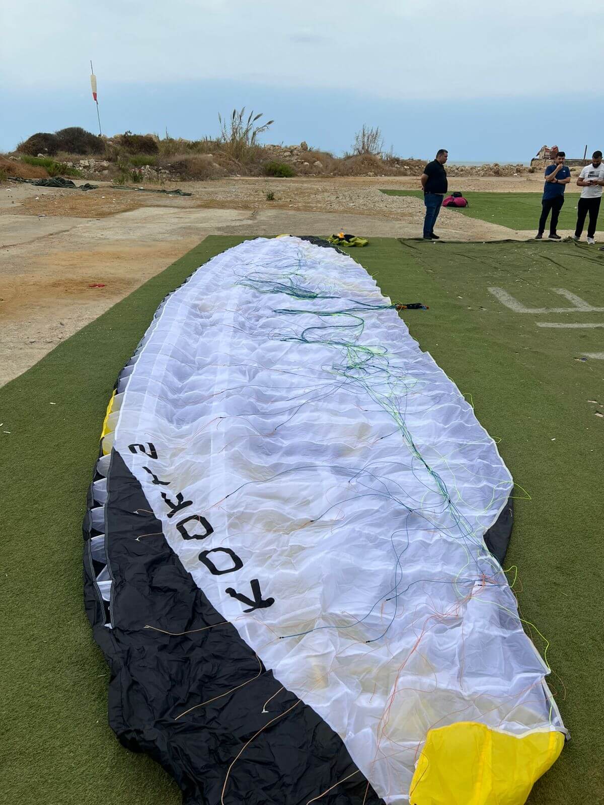 Sky Kooky 2 tandem paraglider in black, white, and yellow colors lying ready for flight — pure acro paraglider for sale, like new condition.