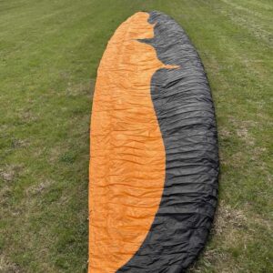 Ozone Enzo 3 black and orange EN CCC 2-liner paraglider laid out on grass ready for high performance XC flight